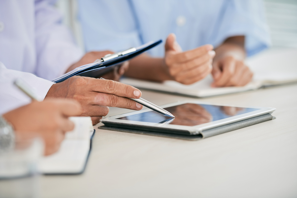 Imagem de close-up de profissionais médicos discutindo informações em tablet digital