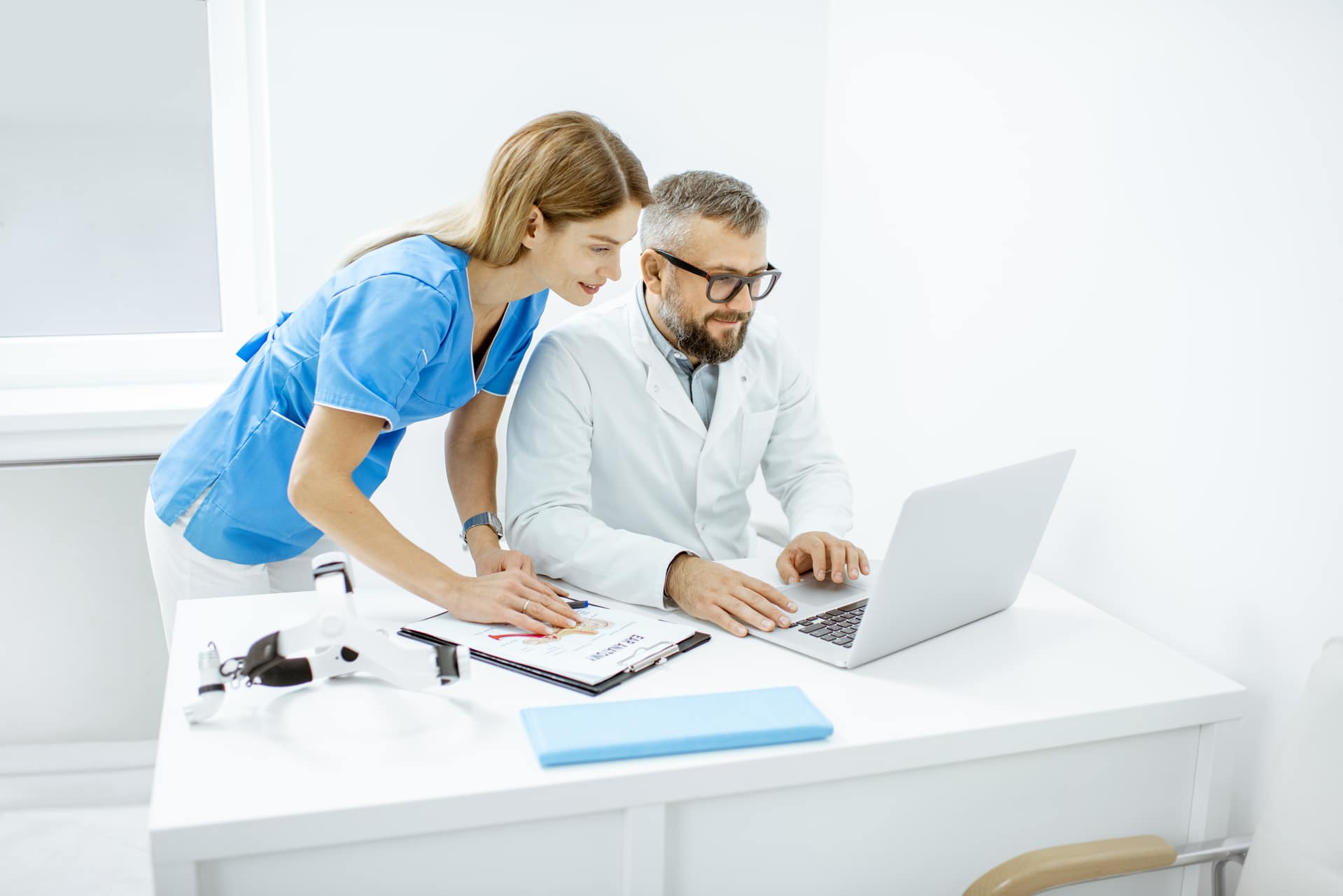 Dois médicos trabalhando com laptop no consultório